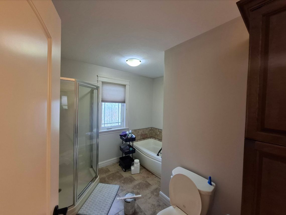 Bathroom with neutral walls, glass shower and white bathtub