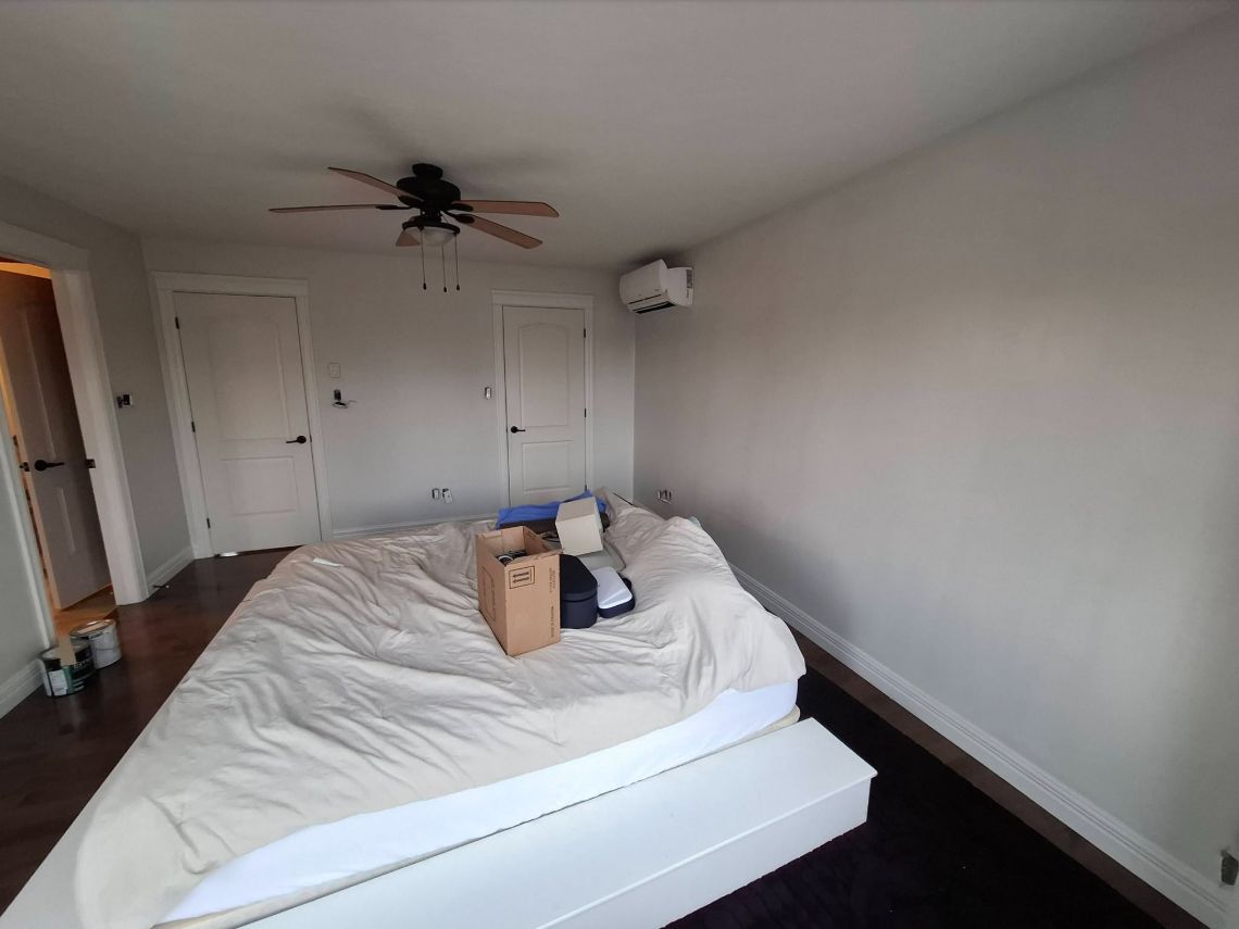 Bedroom with light grey walls, white trim and doors, and a ceiling fan